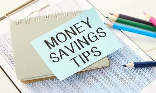 Money Savings Tips, text on small notepad with pen and calculations.