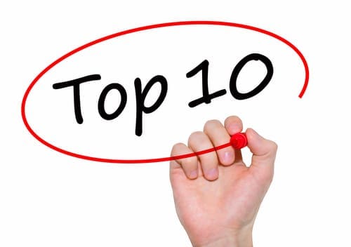 Businessman writing Top 10 with marker on transparent board.