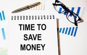 In the notebook the text time TO SAVE MONEY, a number of graphs, reports, pen, glasses.