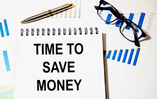 In the notebook the text time TO SAVE MONEY, a number of graphs, reports, pen, glasses.