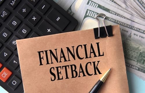 FINANCIAL SETBACK - words on brown paper on the background of calculator and banknotes