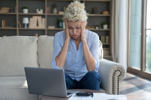 Frustrated concerned mature elder woman worried about finance problems, overspending, money loss, too high price, bankruptcy risk, looking at laptop, calculator in shock