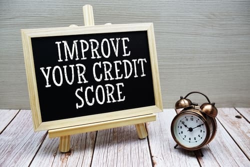 Improve Your Credit Score text written on chalkboard with alarm clock on wooden background