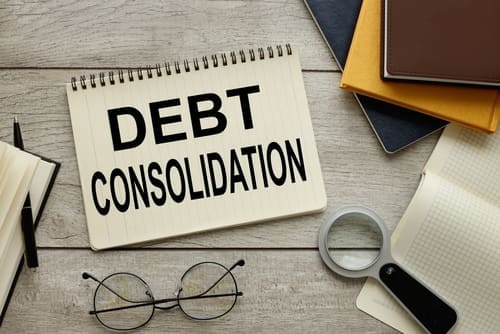 debt consolidation text on notepad with spring. near glasses.