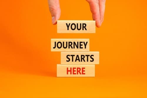 Concept words Your journey starts here on wooden blocks on a beautiful orange table orange background.